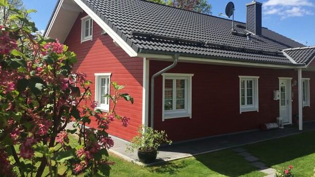 A red house with a sloped roof, white windows, and a satellite dish.