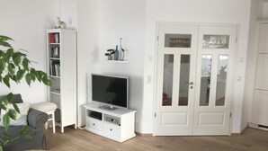 A living room with a TV, bookshelf, and a white door.