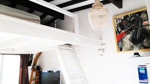 Una habitació amb llit superposat, un penjador de cristall, un quadre i un refrigerador Samsung.