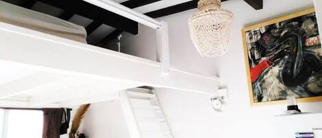 Una habitación con literas, un candelabro, un cuadro y un refrigerador Samsung.