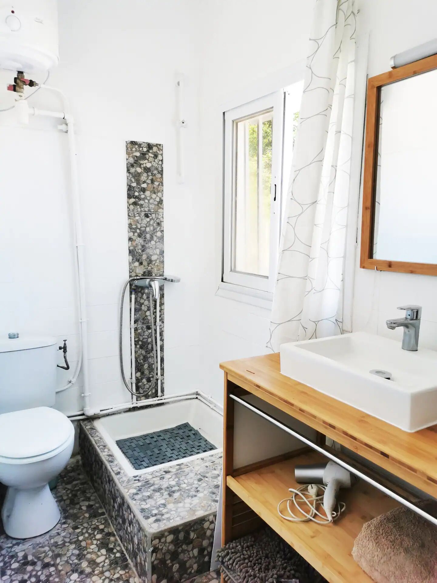 A bathroom with a toilet, a shower, a sink, and a window.