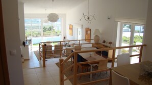 Un grand espace de vie comprenant une table et des chaises, un canapé et une vue sur l’extérieur.