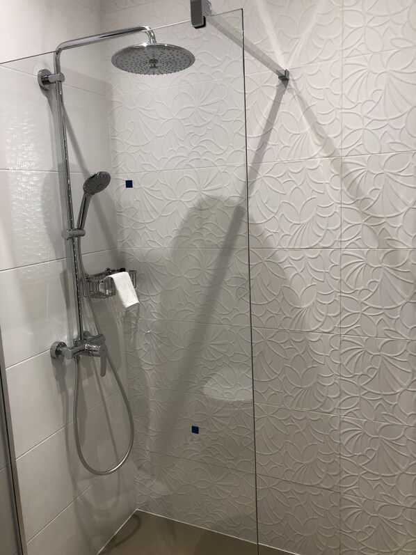 Una ducha con cabezal de ducha de mano y un cabezal de ducha tipo lluvia montado en la pared.