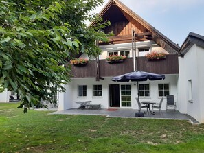 A two-story building with a sloped roof, a balcony with flower boxes, and a patio area with outdoor furniture. - Pure vacation. Arrive and feel good, 2-5 pers. 80sqm, terrace, 2 bedrooms. W-lan (Walkenried)