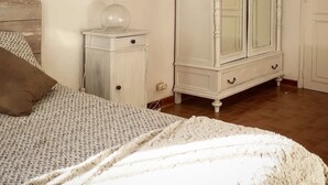 Une chambre à coucher avec un lit, une table de chevet, une lampe, une armoire et un tableau encadré au mur.