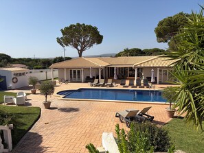 Un espace piscine avec des chaises longues et un patio couvert.
