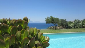 En pool med fri utsikt över havet och bergen i bakgrunden.