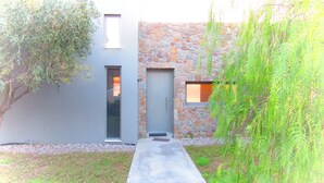 Un bâtiment moderne avec une façade en pierre, un chemin en béton et une porte.