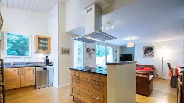 A modern kitchen with wooden cabinets, a dishwasher, and a central island with drawers.
