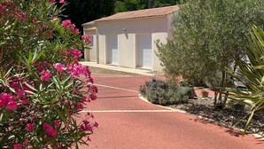 A pathway leading to a building with a tiled roof and white shutters.