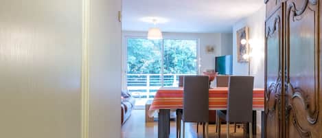 A hallway leading to a dining area with a wooden floor, a dining table with chairs, and a large wooden cabinet.