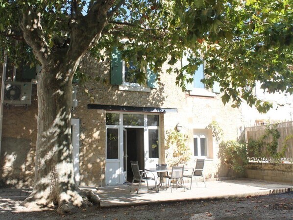 A rustic stone building with a covered patio, outdoor seating, and a large tree providing shade. - cottage with terrace, BBQ, the charm of the countryside, ideal couple (Raissac-D'aude)