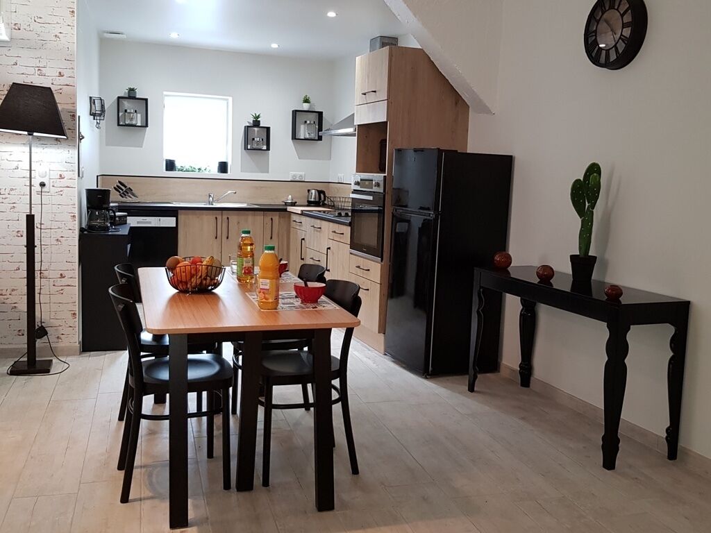 Een moderne keuken met een eettafel, stoelen en een koelkast.