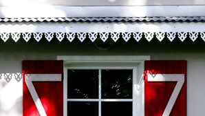 Un edificio blanco con ventana y contraventanas rojas.