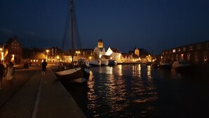 A waterfront scene with buildings, boats, and a prominent tower. - Apartment 'Am Poeler Tor' in the old town of Wismar (Wismar)