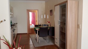A modern kitchen with a dining area, featuring a wooden cabinet, a dining table with chairs, and a small rug. - Apartment 'Am Poeler Tor' in the old town of Wismar (Wismar)