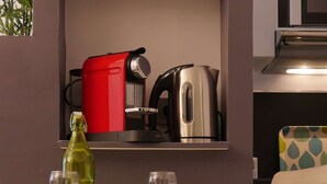 A modern kitchen with a red and black coffee maker, a silver kettle, and a green bottle on the counter. - Studio Premium Toulouse Zénith - Parking,  Métro et Netflix (Toulouse)