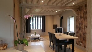 A dining area with a table and chairs, a potted plant, and a window with curtains. - AN INDEPENDENT HOUSE FOR 4 PEOPLE AT PONT L'EVEQUE, BETWEEN HONFLEUR AND DEAUVILLE  (Coudray-Rabut)