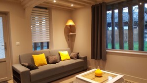 A living room with a grey sofa, yellow cushions, a floor lamp, and a window with curtains. - AN INDEPENDENT HOUSE FOR 4 PEOPLE AT PONT L'EVEQUE, BETWEEN HONFLEUR AND DEAUVILLE  (Coudray-Rabut)