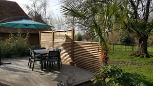 A wooden deck with a table and chairs, a green umbrella, and a wooden fence. - AN INDEPENDENT HOUSE FOR 4 PEOPLE AT PONT L'EVEQUE, BETWEEN HONFLEUR AND DEAUVILLE  (Coudray-Rabut)