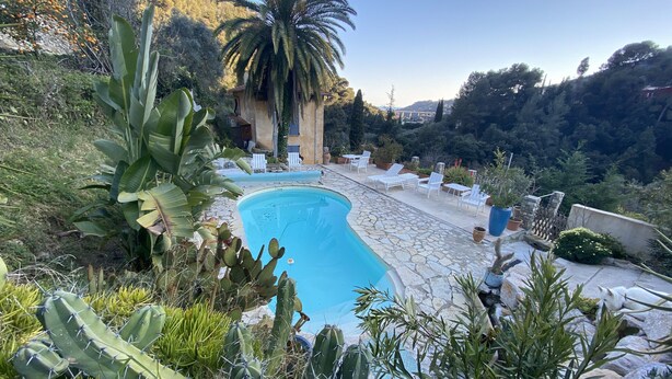 A pool area with a stone deck, surrounded by cacti and palm trees, and a view of a mountainous landscape. - Rest and nature in Menton, sea and private pool. Pet-friendly. (castellar)