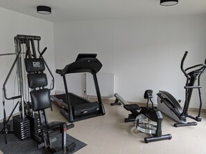 A home gym with a treadmill, elliptical, and weight machine.