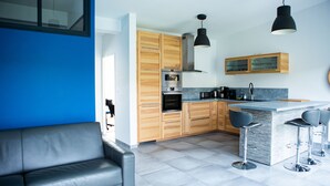 Una cocina moderna con armarios de madera, horno empotrado y una zona de bar con taburetes.