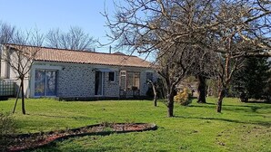 A stone building with a tiled roof, surrounded by a grassy yard and leafless trees. - HOUSE 4 PERS + SPA + HEATED POOL CALM & REST IN MARAIS POITEVIN VENDEE (Liez)
