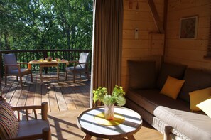 A wooden deck with a table and chairs, a sofa, and a potted plant.