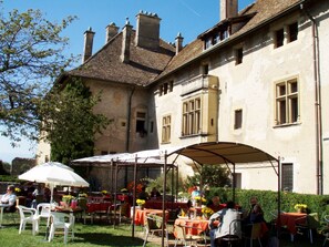 Guests can dine in the shaded courtyard, surrounded by the building's classic facade and evenly spaced windows.