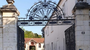 A gated entrance with a wrought iron gate, a stone building with a tiled roof, and a sign indicating private property. - Large atypical charming house entirely renovated. (Jonzac)