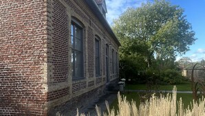 Un edificio de ladrillo con ventanas amplias y un jardín delantero.