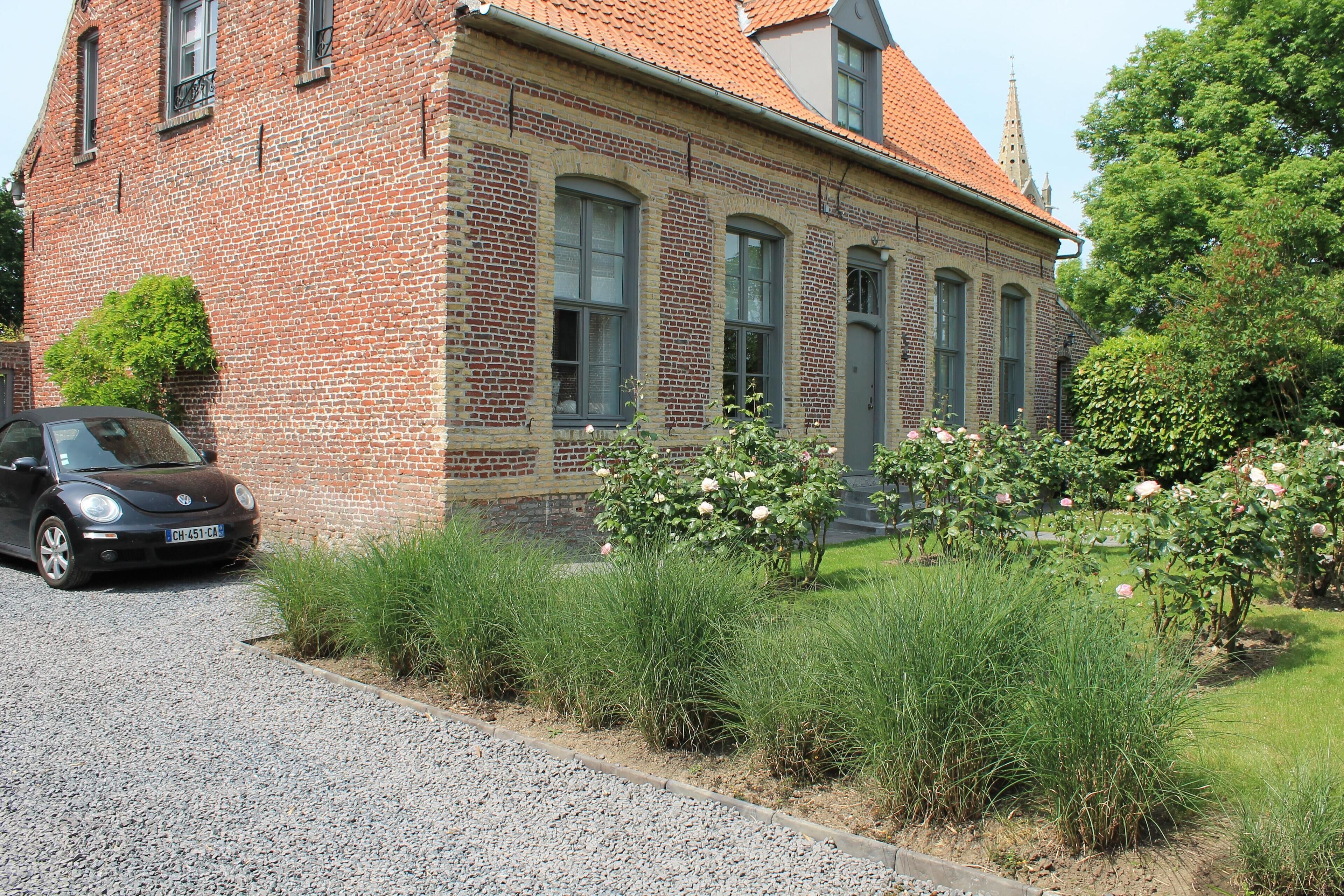 Een bakstenen gebouw met een grindpad en een auto aan de zijkant.