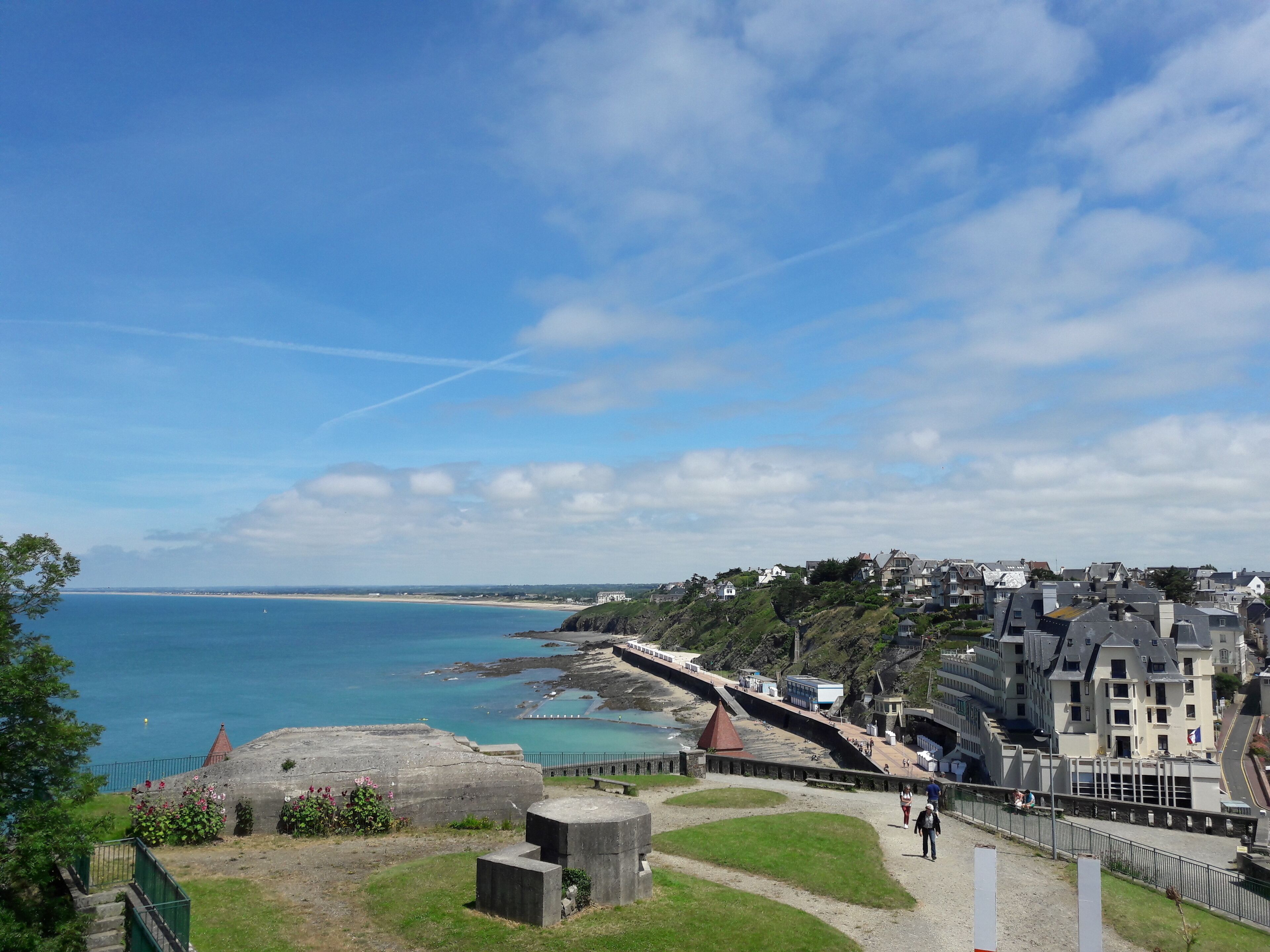 A coastal town with a prominent fort, a promenade, and buildings along the sea.