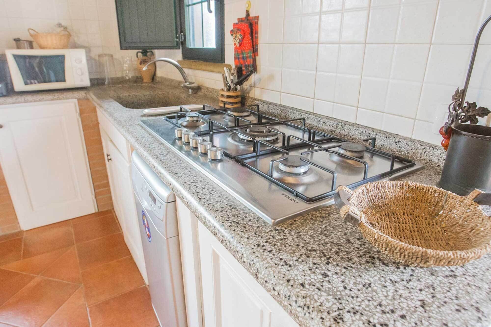Een keuken met een gasfornuis, een magnetron en een spoelbak.