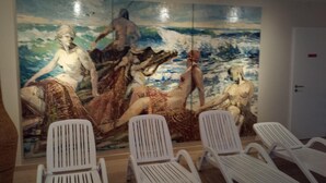 Ein Zimmer mit einer großen Wandmalerei von Meereslandschaften und Liegesesseln.