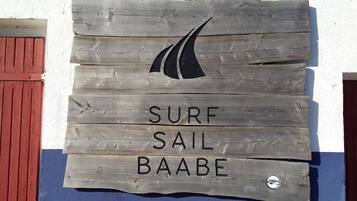 Un letrero de madera con la inscripción 'SURF SAIL BAABE' y un logotipo de velero.