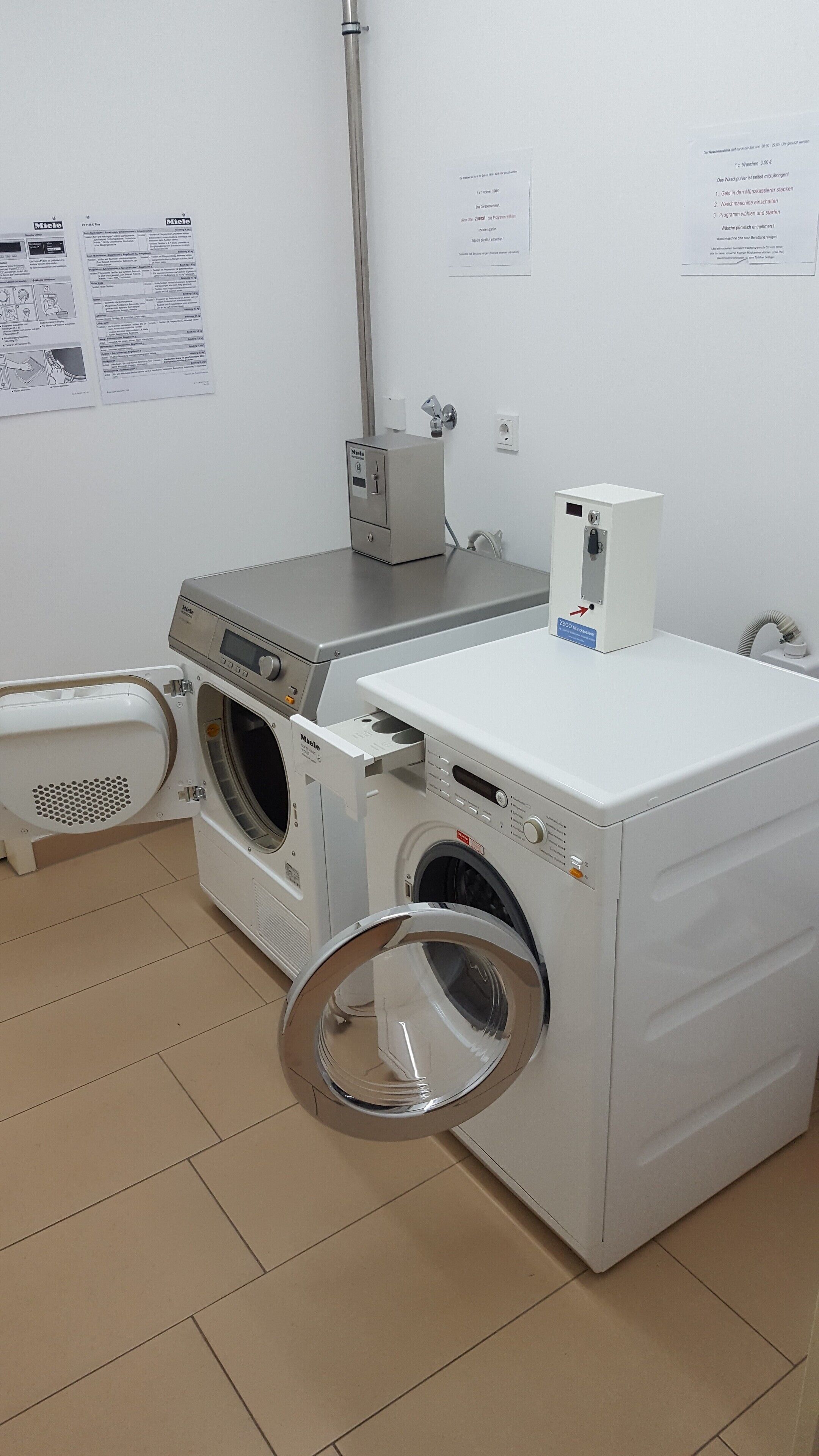 A laundry room with a front-loading washing machine, a dryer, and a utility room with a water heater and electrical outlets.