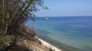 Eine Küstenlandschaft mit freiem Blick auf das Meer, einem Sandstrand und einem Schiff in der Ferne.