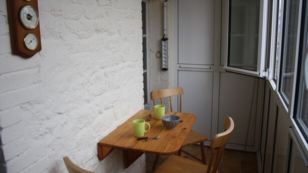 A small dining area with a wooden table, two chairs, a bowl, and two mugs. A wall clock is visible on the left. - Central apartment near train station  (Saint-Malo)