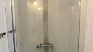 A glass-enclosed shower stall with a tiled wall and a showerhead. - Central apartment near train station  (Saint-Malo)