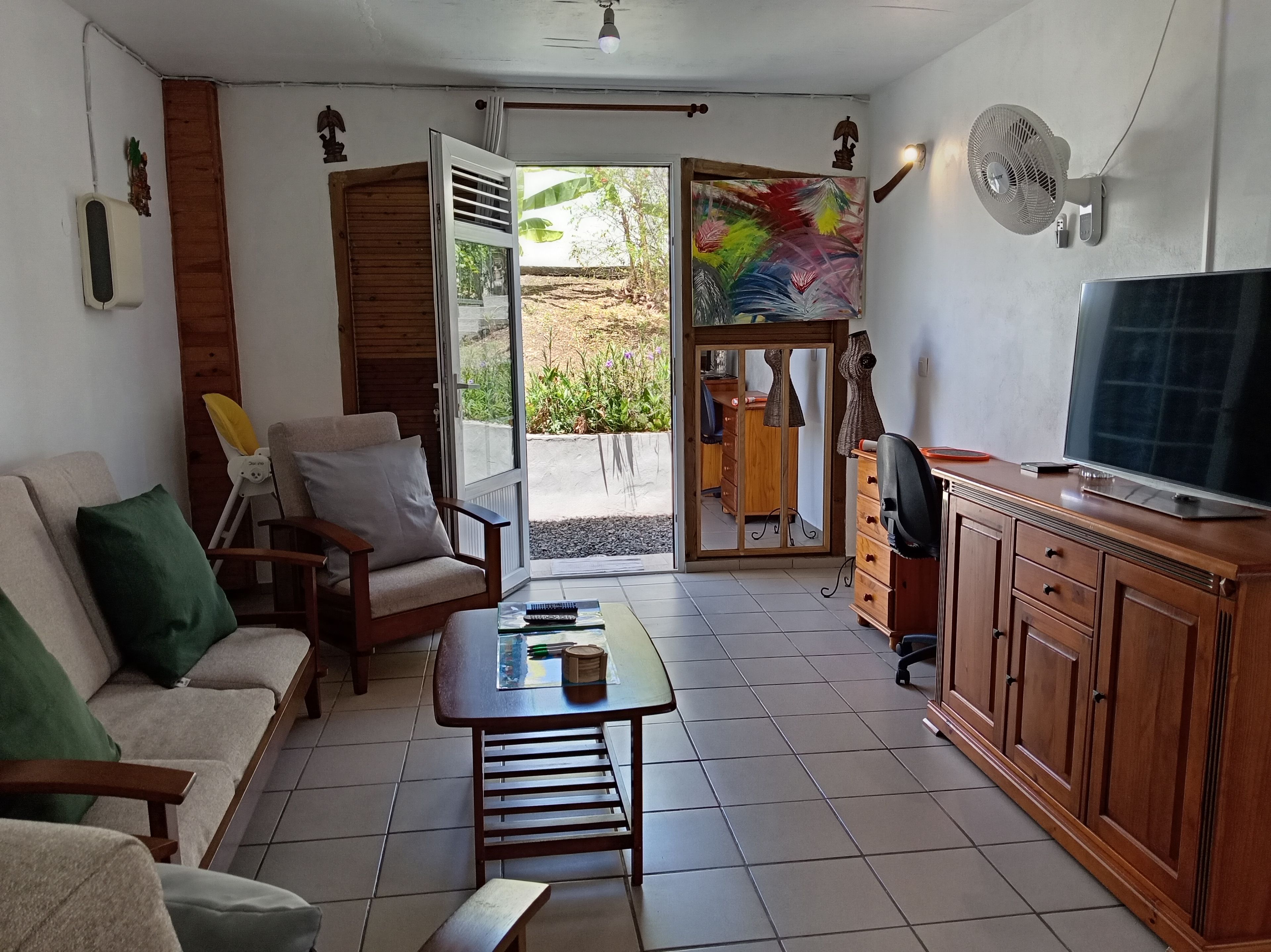 Una sala de estar con sofá, una mesa de centro, televisor y puerta corrediza de vidrio que da a un área exterior.