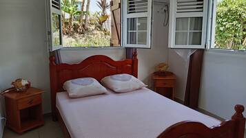 A bedroom with a wooden bed, two bedside tables, and a window with shutters.