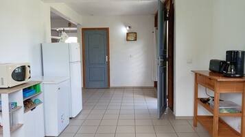 A kitchen with a microwave, refrigerator, and a coffee maker on a wooden table.