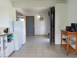 A kitchen with a microwave, refrigerator, and a coffee maker on a wooden table. - Villa Le Gommier - Rental in Le Moule, Guadeloupe (LE MOULE)