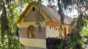 Une charmante maison avec un toit en pente, un petit porche et un jardin agrémenté de chemins de gravier.