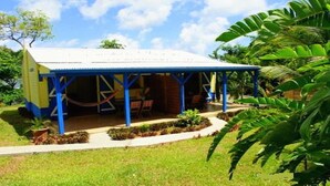 A small, single-story building with a blue roof and a covered porch. - 2 - Exotic Bungalow T2 & Large Garden near beach  (LA TRINITE)