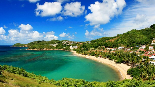 A coastal landscape with a beach, clear blue waters, and a backdrop of hills with scattered buildings. - 2 - Exotic Bungalow T2 & Large Garden near beach  (LA TRINITE)