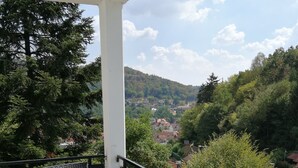 A balcony with two chairs and a table, overlooking a scenic view of a village and hills. - Quiet vacation oasis with a beautiful view over Bad Lauterberg (Bad Lauterberg)