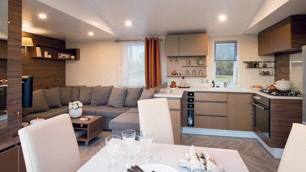 A modern kitchen with a dining area, featuring a sofa, dining table, and kitchen appliances. - Mobilhome family 6/7 Persons (Saint-Brevin-Les-Pins)